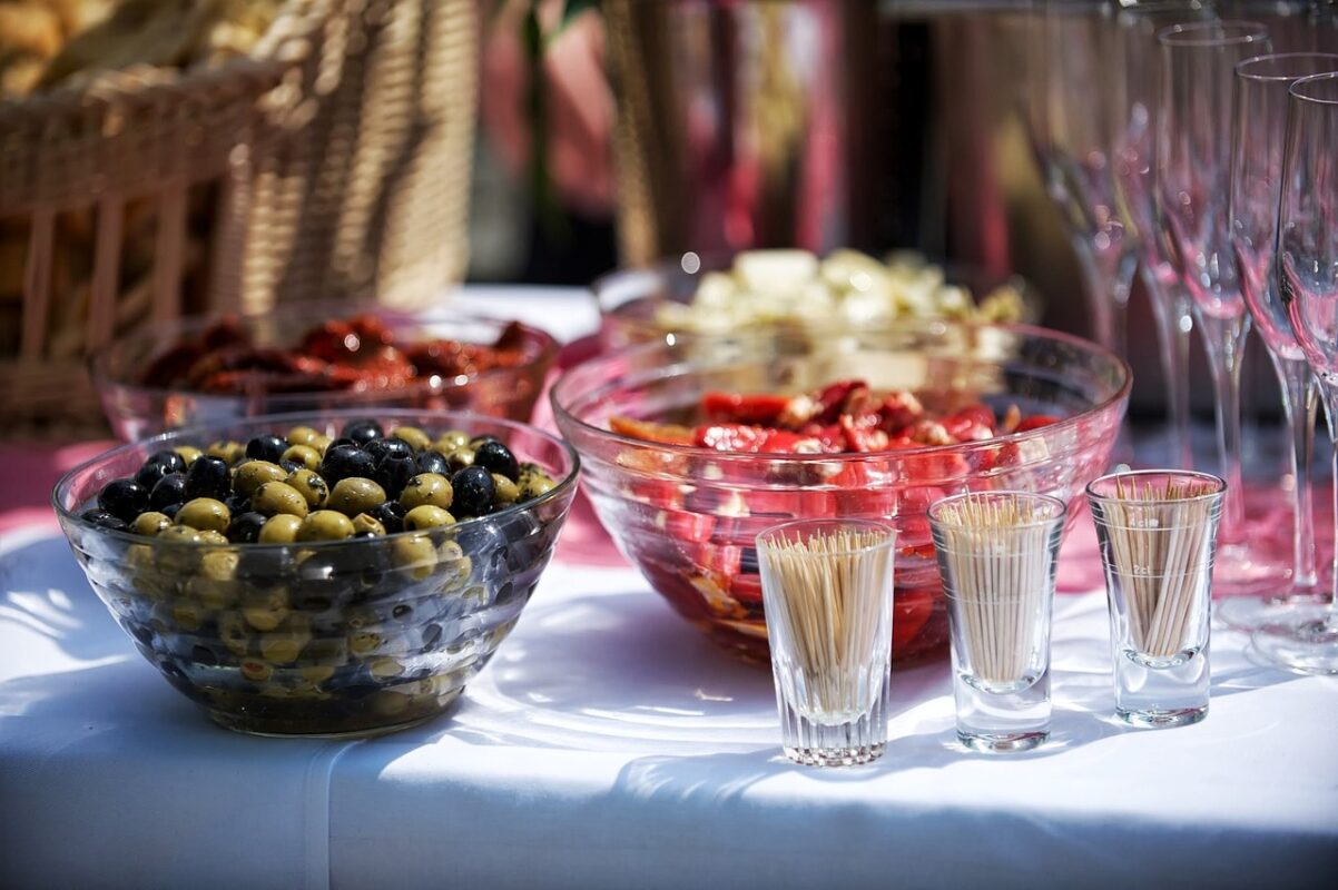 Catering buffet table with serving bowls, champagne flutes and pots of cocktail sticks