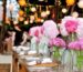 Evening reception table under paper lanterns and string lights, set with napkins and flowers